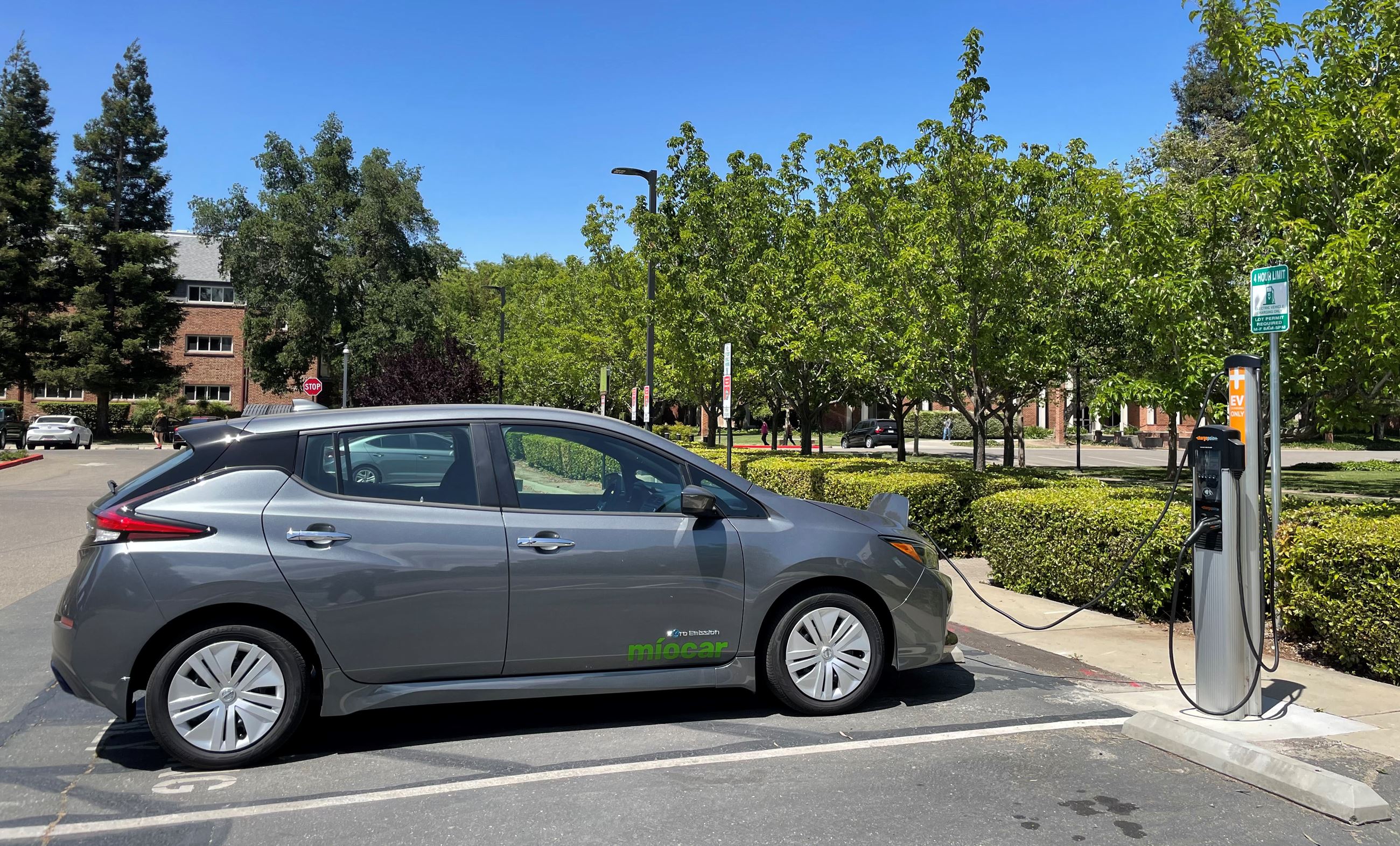 Image shows an electric car plugged into a charging station.